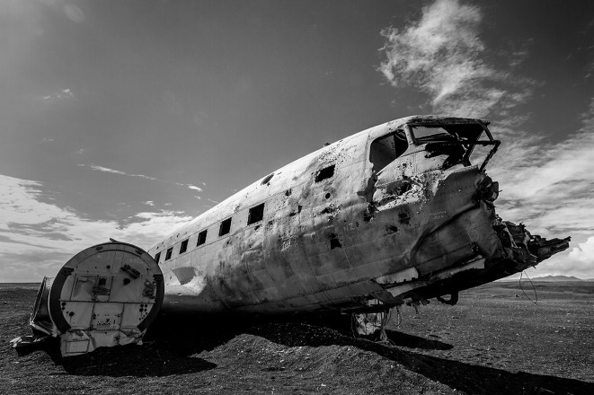 Flugzeugwrack inmitten einer schwarzen Wüste